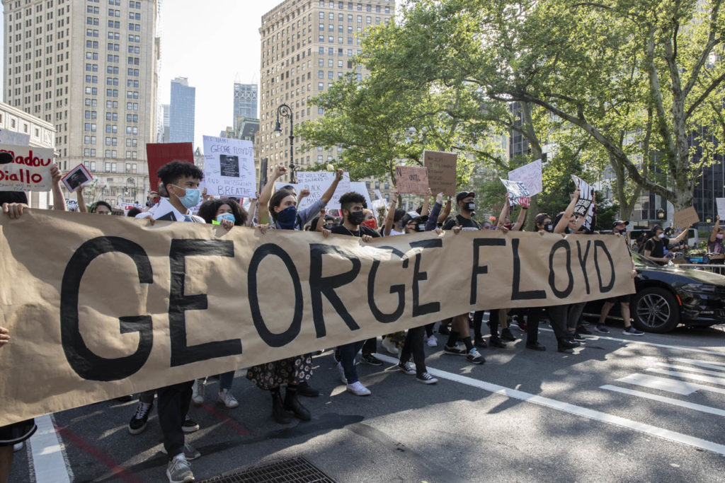 Protestors in Foley Square march with a sign honoring George Floyd. Image courtesy Ventiko.