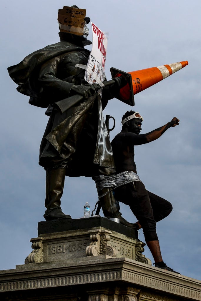 A man tapes himself to the Colorado Soldiers Monument in front of the Colorado State Capitol during the fourth day of protests in the aftermath of the death of George Floyd on May 31, 2020 in Denver, Colorado. Photo by Michael Ciaglo/Getty Images.