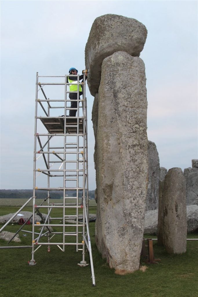 Jake Ciborowski using a portable x-ray fluorescence spectrometer. to conduct surface readings on one of the 52 sarsen stones at Stonehenge. Photo by David Nash.