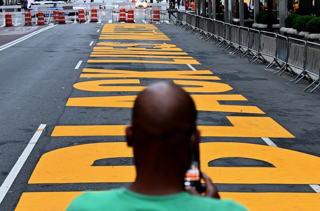 A man uses his cell phone to take a picture of a newly painted Black Lives Matter mural outside of Trump Tower on Fifth Avenue on July 10, 2020 in New York City. Photo by Angela Weiss/AFP/Getty Images.