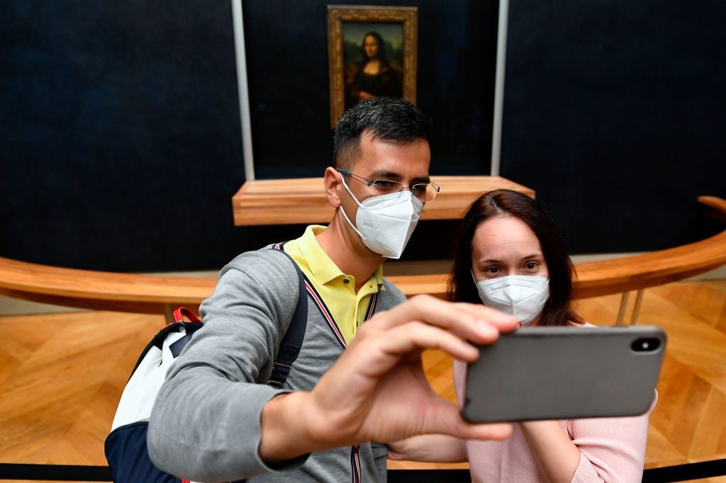Visitors wearing face masks take selfies in front of Mona Lisa during the reopening to the public of the Louvre Museum on July 06, 2020 in Paris, France. Photo by Aurelien Meunier/Getty Images.