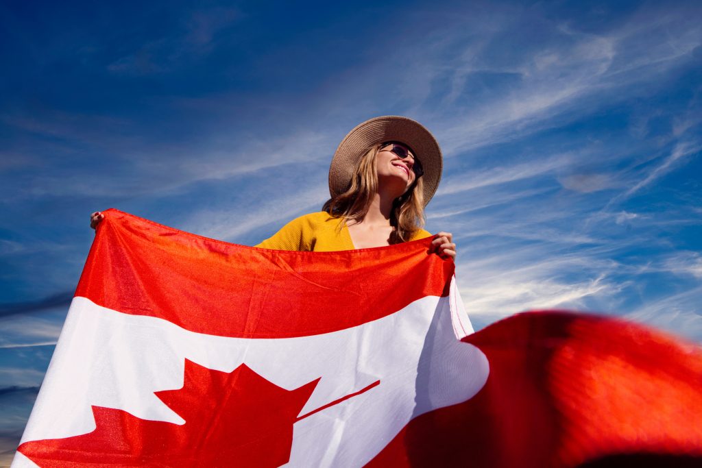 A woman proudly carrying the Canadian flag. Photography by Andre Furtado. Courtesy of Pexels.