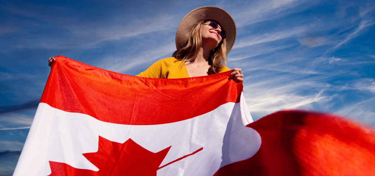 A woman proudly carrying the Canadian flag. Photography by Andre Furtado. Courtesy of Pexels.