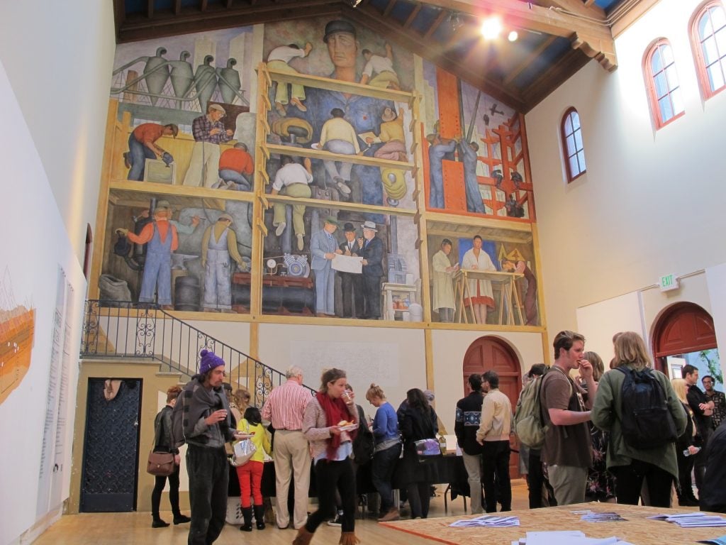 Students gathering below Diego Rivera's famous mural at the San Francisco Art Institue. Image by Gary Stevens, via Flickr.