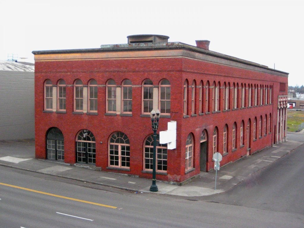 A red brick building on an empty street corner. Originally a commercial laundry built in 1909, the building has housed Yale Union since 2008, but is now being given to the Native Arts and Culture Foundation.