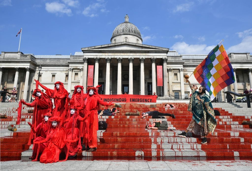 Extinction Rebellion pour dye down the steps near the National Gallery in Trafalgar Square, London, during a protest in solidarity with indigenous communities in Brazil who are dying from Covid-19. Photo by Dominic Lipinski/PA Images via Getty Images.