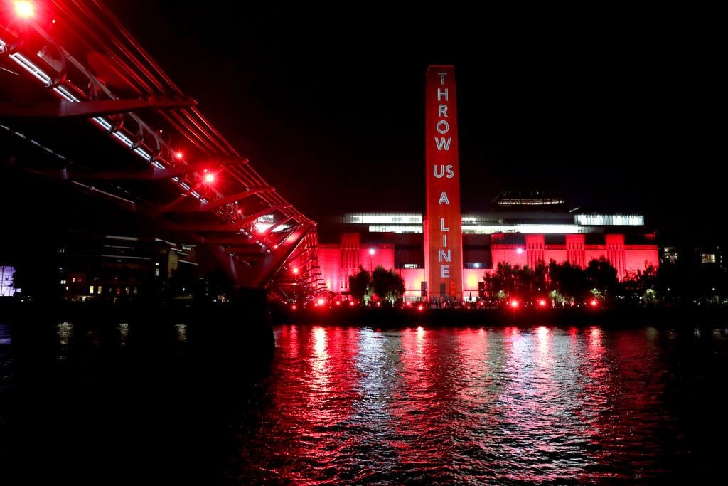 The Tate Modern is lit up in red as supporters also shine red lights from the Millennium Bridge as part of the #WeMakeEvents' 'Throw Us a Line Campaign' supporting on August 11, 2020 in London, England. Photo by Chris Jackson/Getty Images.