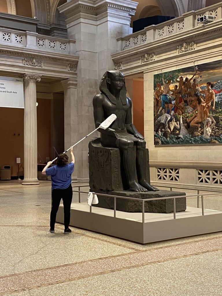 An employee giving a once-over to an Egyptian sculpture at the recently reopened Metropolitan Museum of Art. Photo: Zachary Small.