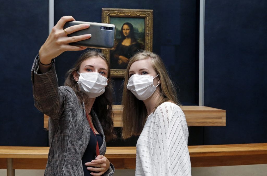 Visitors wearing face masks take a selfie with the painting of "Mona Lisa" by Leonardo Da Vinci at the Louvre museum. (Photo by Chesnot/Getty Images)