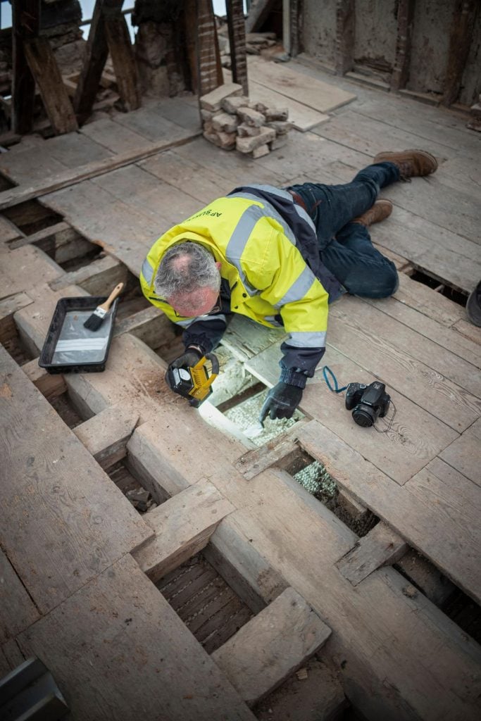 English archaeologist Matt Champion looking under the floorboards at Oxburgh Hall. Courtesy of the National Trust. Photo: Mike Hodgson.