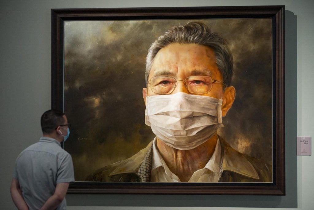 A visitor looks at a portrait painting depicting Chinese respiratory specialist Zhong Nanshan during an art exhibition on novel coronavirus prevention at National Museum of China. (Photo by Hou Yu/China News Service via Getty Images)