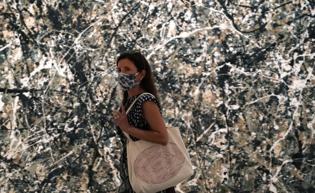 A woman walks past Jackson Pollock's Autumn Rhythm Number 30 in the newly reopend MoMA. (Photo by TIMOTHY A. CLARY/AFP via Getty Images)
