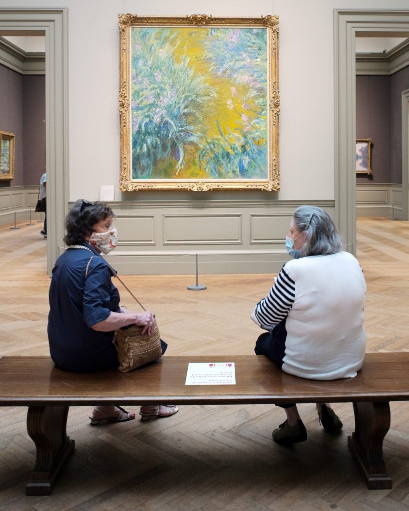 Two friends in face masks sit in front of Claude Monet's paintings at the Metropolitan Museum of Art during its first day open to members since March on August 27, 2020 in New York City. Photo by Taylor Hill/Getty Images.