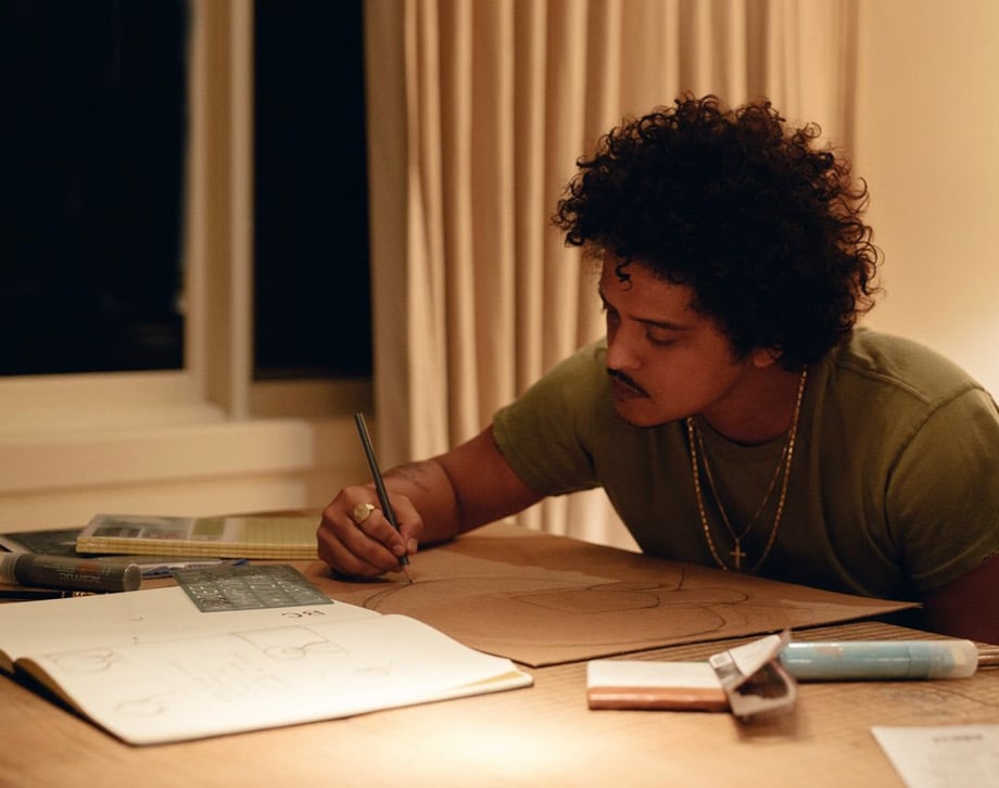 Bruno Mars drawing his sign <em>Untitled</em> for the “Show Me the Signs” auction. Photo courtesy of the African American Policy Forum.