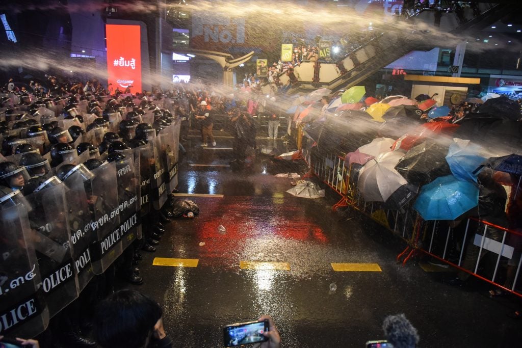 Pro-democracy protesters in Thailand covering themselves from the water cannons with umbrellas. Photo by Yuttachai Kongprasert/SOPA Images/LightRocket via Getty Images.