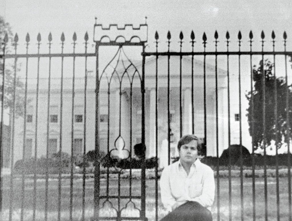 John Hinckley sitting on thefence wall in front of the White House. Courtesy of Getty Images.