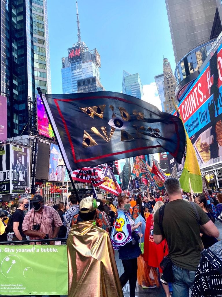 Michele Pred's Vote Feminist March in Times Square for the Wide Awakes, with Pablo A. Medina waving his flag in the foreground. Photo by Sarah Cascone. 