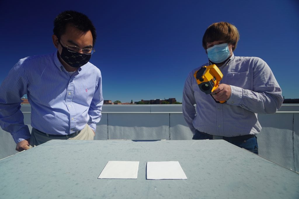 Purdue researchers Xiulin Ruan (left) and Joseph Peoples compare the cooling performance of white paint samples on a rooftop. Photo by Jared Pike/Purdue University.