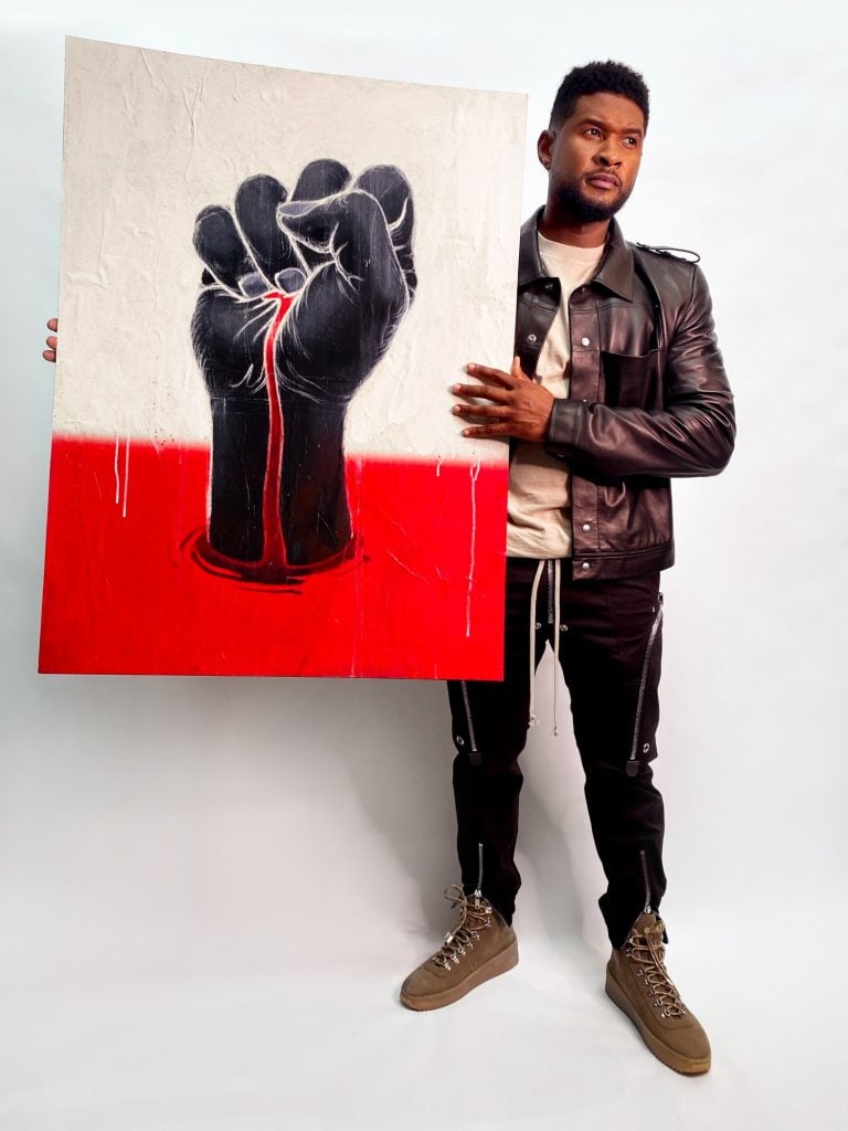 Usher with his and James Jean's sign Can't Breath for the “Show Me the Signs” auction. Photo courtesy of the African American Policy Forum.