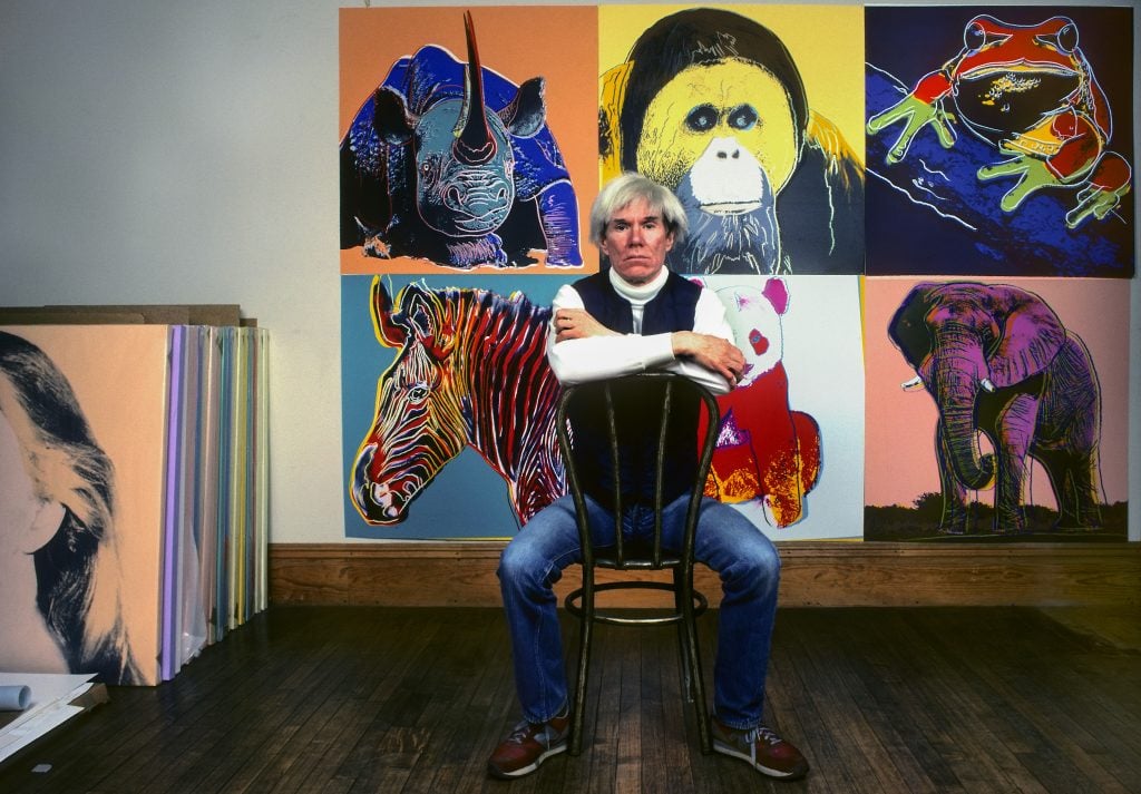 Andy Warhol in front of several paintings in his "Endangered Species" series at his studio, the Factory, in Union Square, New York, New York, April 12, 1983. (Photo by Brownie Harris/Corbis via Getty Images)