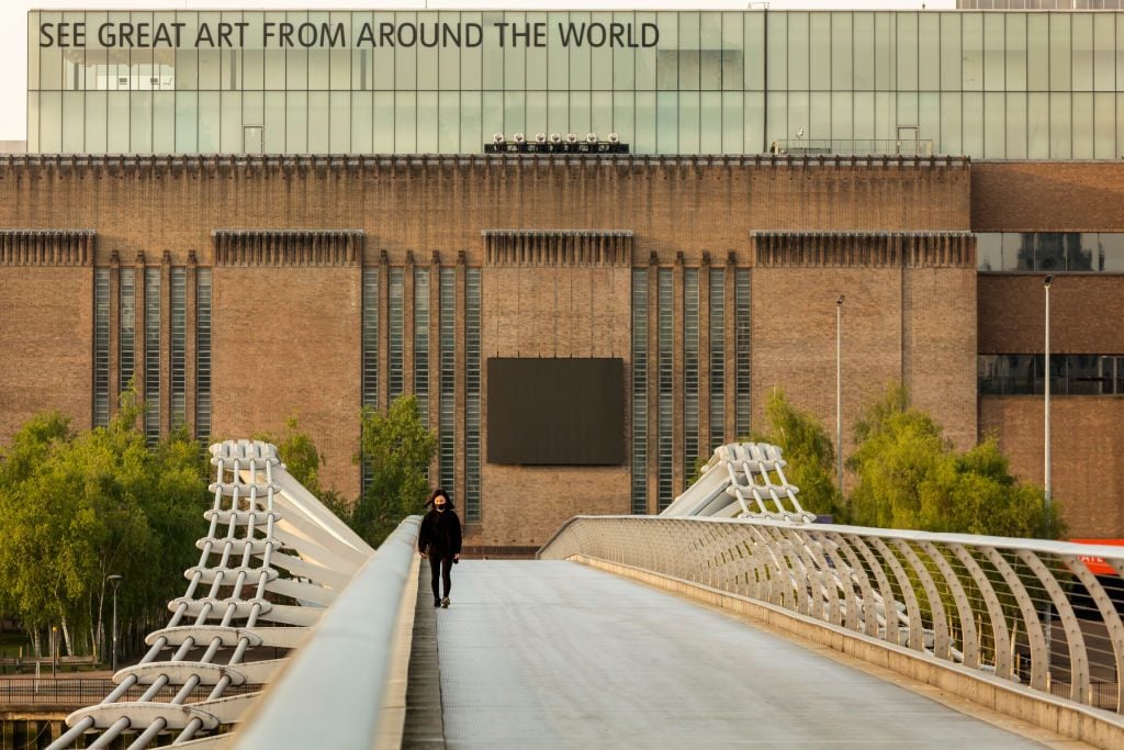A woman walks past the Tate Modern in London. Photo by Barry Lewis/InPictures via Getty Images.