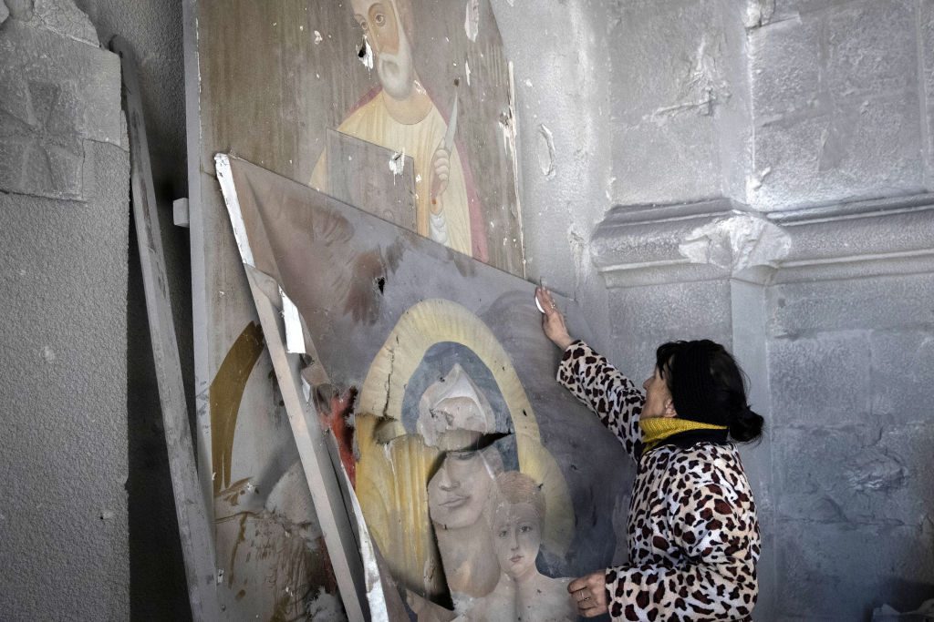 A local resident wipes a religious icon at the Ghazanchetsots Cathedral (Holy Savior Cathedral), partially destroyed in a shelling attack by the Azerbaijani armed forces. Photo: Stanislav KrasilnikovTASS via Getty Images.