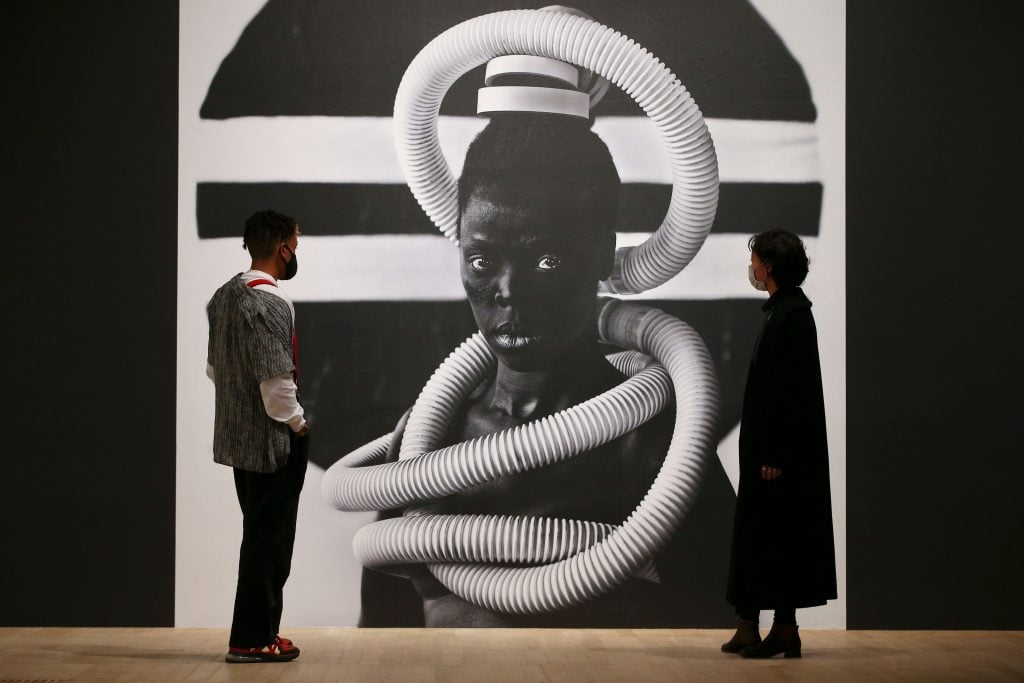 Tate visitors pose in front of a self portrait photograph from an ongoing series entitled "Somnyama Ngonyama" by South African visual activist Zanele Muholi during a press view of an exhibition at the Tate Modern gallery in London on November 3, 2020. (Photo by HOLLIE ADAMS/AFP via Getty Images)