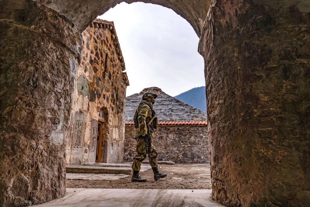 A Russian peacekeeper walks past along a yard of the 12th-13th century Dadivank Monastery, outside the town of Kalbajar on November 16, 2020, after the monastery was put under their protection as part of the peace agreement putting an end to the military conflict between Armenia and Azerbaijan over the breakaway region of Nagorno-Karabakh. Photo: Andrey Borodulin/AFP via Getty Images.