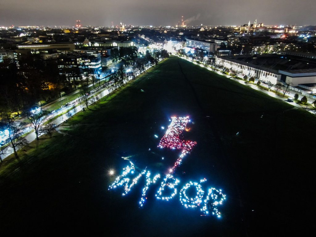 An aerial view of people who gather and light up their smartphones or lanterns to form an inscription saying WYBÓR (choice in English) along with a lightning bolt. Photo: Omar Marques/Getty Images.