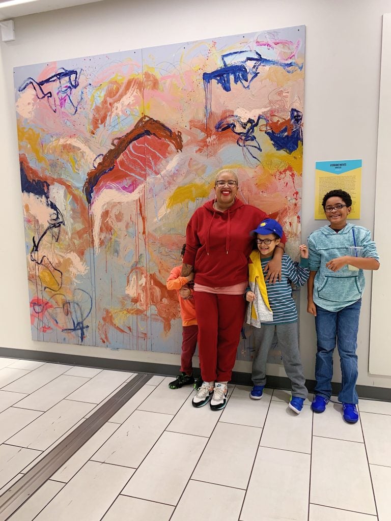 A'Driane Nieves and her children with a mural she did for the Fashion District Philadelphia in 2019. Photo