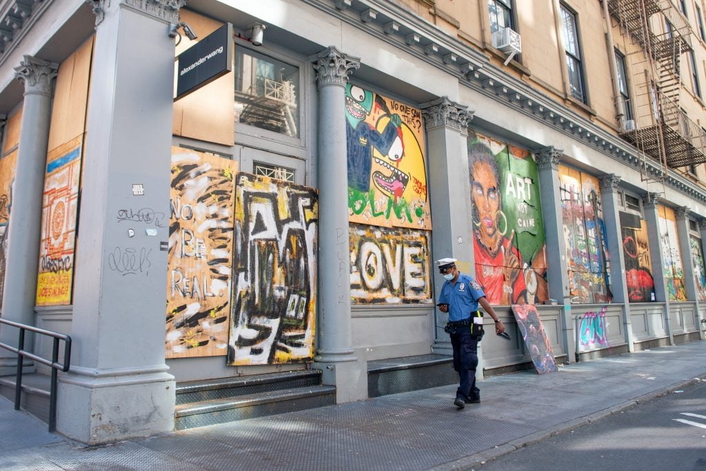 An NYPD traffic officer walks past street art in SoHo as the city continues Phase 4 of re-opening following restrictions imposed to slow the spread of coronavirus on August 20, 2020 in New York City. Photo by Alexi Rosenfeld/Getty Images.