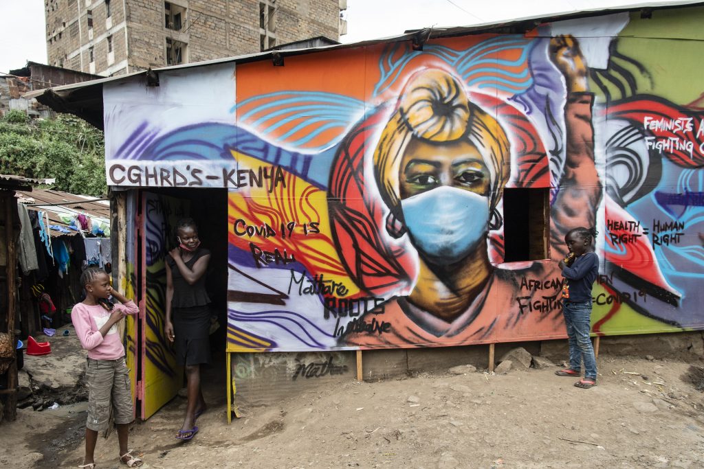 A girl walks out of a building decorated with educational graffiti about safety measures and COVID-19 on July 6, 2020 in Nairobi, Kenya. Photo by Alissa Everett/Getty Images.