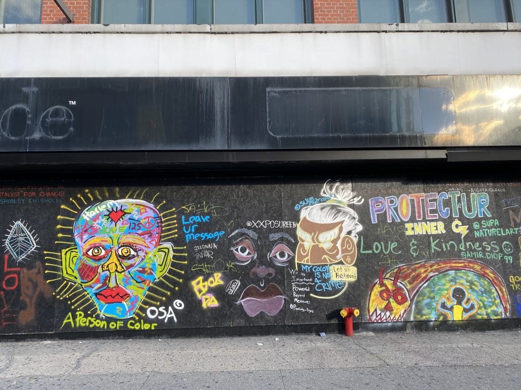 Street art on a boarded up storefront in Harlem. Photo by Sarah Cascone.