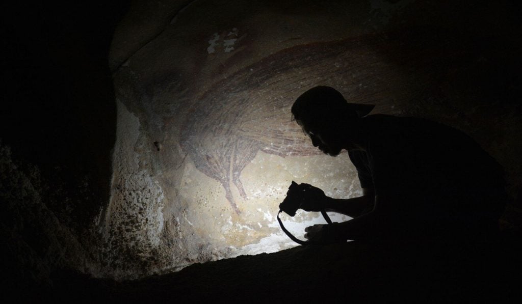 An archaeologist with the prehistoric painting. Photo by Adhi Agus Oktaviana.