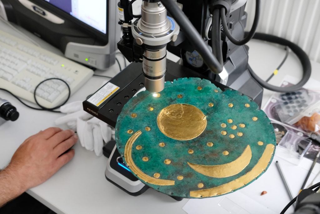 A replica of the Nebra Sky Disk being examined with a microscope in the workshop of the State Office for Monument Preservation and Archaeology Saxony-Anhalt. Photo by Sebastian Willnow/dpa-Zentralbild/dpa/picture alliance via Getty Images.