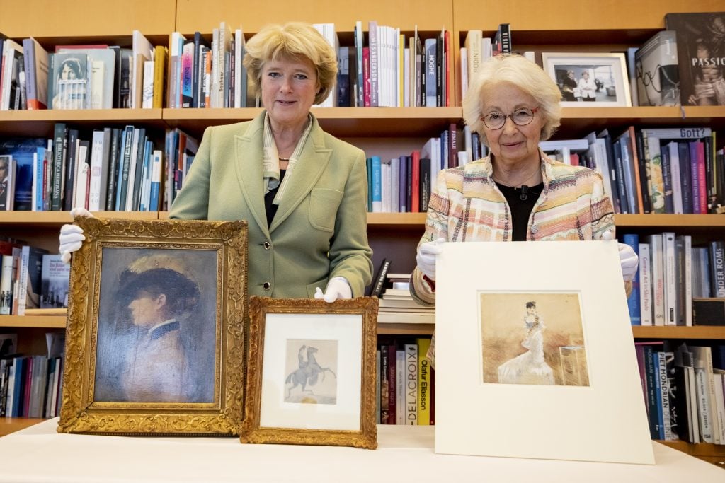 Monika Grütters, Germany's Minister of State for Culture, returns three works of art identified as Nazi looted art to Francine Kahn, grandniece of the art collector Armand Dorville, in January 2020. The works in question are the watercolor <em>Lady in an evening gown</em> and the painting <em>Portrait of a Lady</em> by Jean-Louis Forain, both from the collection of Cornelius Gurlitt, as well as the drawing </em>Amazon with rearing horse</em> by Constantin Guys, which was last in private ownership. Photo by Christoph Soeder/dpa/picture alliance via Getty Images.