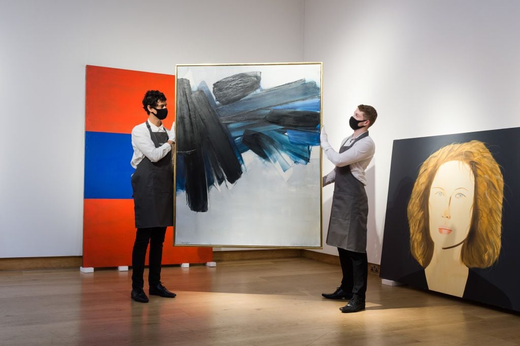 Staff members present a work by Pierre Soulages at Christie's. Photo by WIktor Szymanowicz/NurPhoto via Getty Images.
