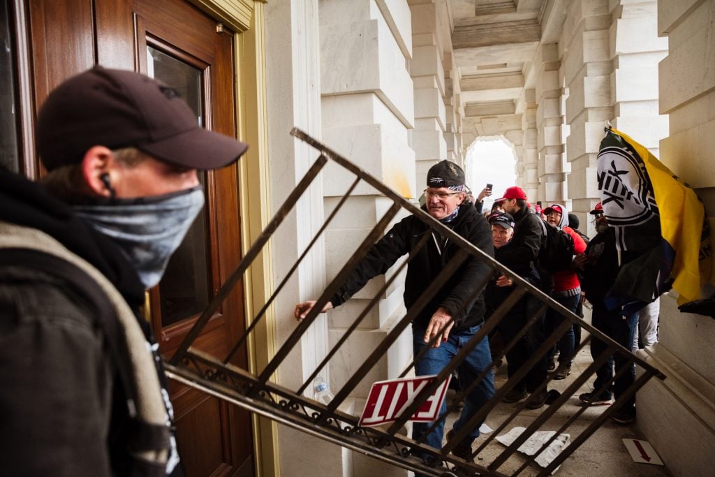 A member of a pro-Trump mob bashes an entrance of the Capitol Building in an attempt to gain access on January 6, 2021 in Washington, DC. A pro-Trump mob stormed the Capitol, breaking windows and clashing with police officers. Trump supporters gathered in the nation's capital today to protest the ratification of President-elect Joe Biden's Electoral College victory over President Trump in the 2020 election. Photo by Jon Cherry/Getty Images.