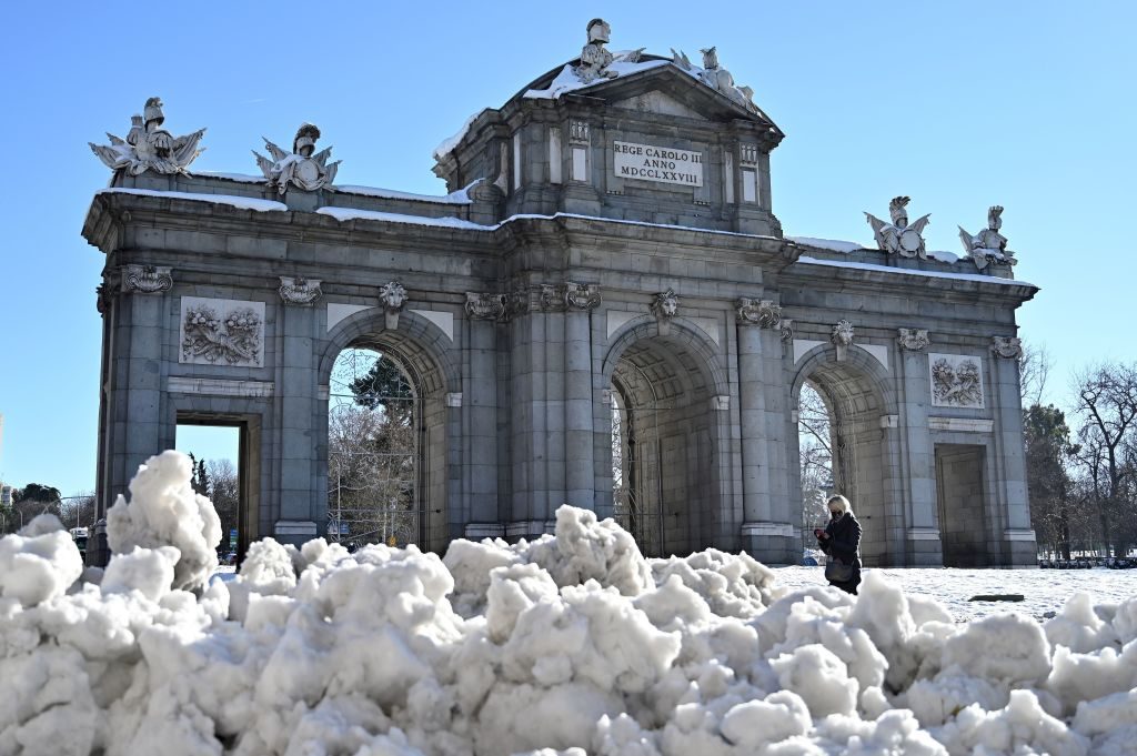 A woman walks by Puerta de Alcala after a heavy snowfall in Madrid on January 11, 2021. Photo by Gabriel Bouys/AFP via Getty Images.