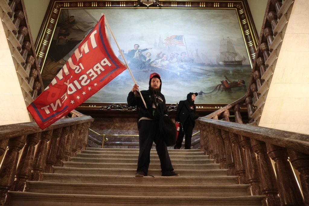 A rioter holds a Trump flag inside the US Capitol Building near the Senate Chamber on January 06, 2021 in Washington, DC. Photo by Win McNamee/Getty Images.
