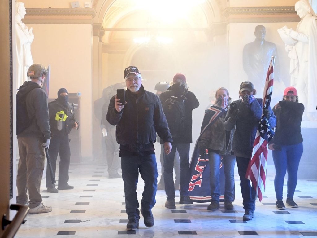 Supporters of US President Donald Trump enter the Capitol as tear gas fills the corridor on January 6, 2021, in Washington, DC. (Photo by Saul Loeb/AFP via Getty Images.)