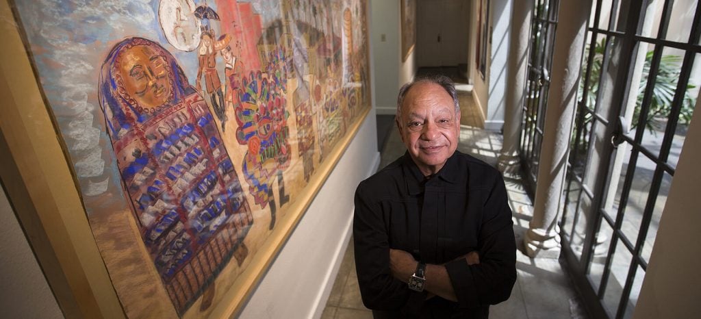 Cheech Marin with a work from his collection of Chicano art. Photo courtesy of the Cheech Marin Center for Chicano Art, Culture & Industry of the Riverside Art Museum.