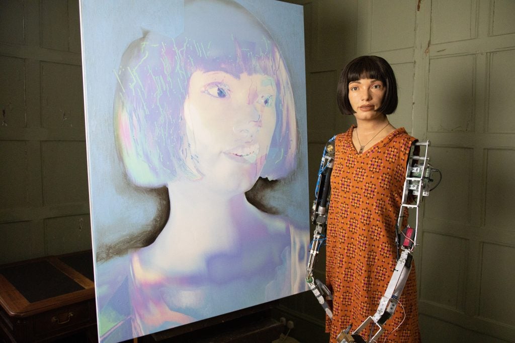 Ai-Da the robot artist with his self-portraits.  Photo courtesy of the Design Museum.