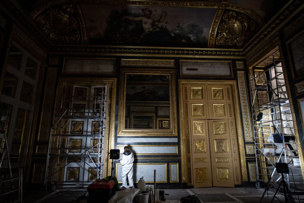 Painters of the restoration department of the Louvre Museum at work. Photo by MARTIN BUREAU/AFP via Getty Images.