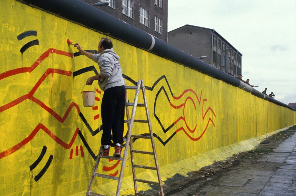 Keith Haring painting a mural in Berlin, October 1986. Photo by Patrick PIEL/Gamma-Rapho via Getty Images.