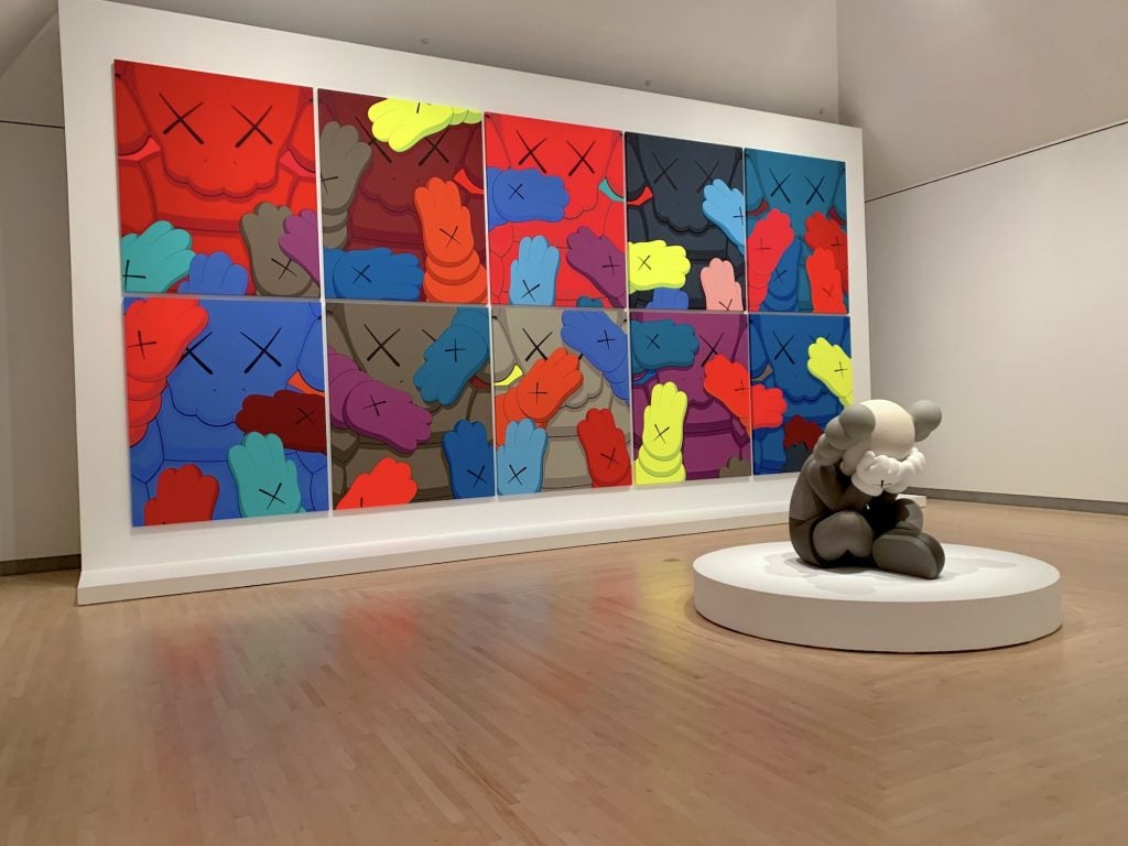KAWS, <em>Separated</em> (2019) with works from the "Urge" series in the background. (Photo by Ben Davis)