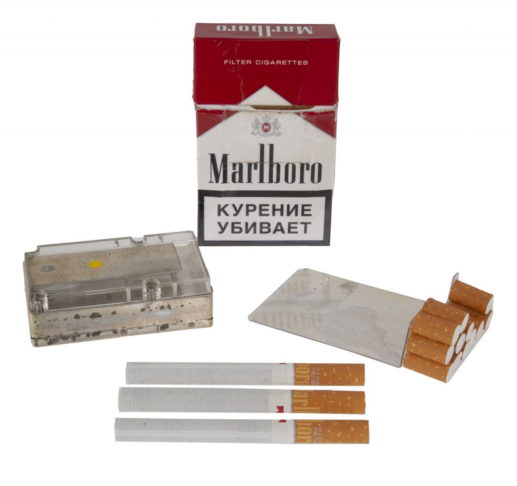 A Russian FSB spy pack of Marlboro brand cigarettes containing a hidden digital camera, with the lens operating through a small hole on the side. Includes remote control unit. Courtesy Julien's Auctions.