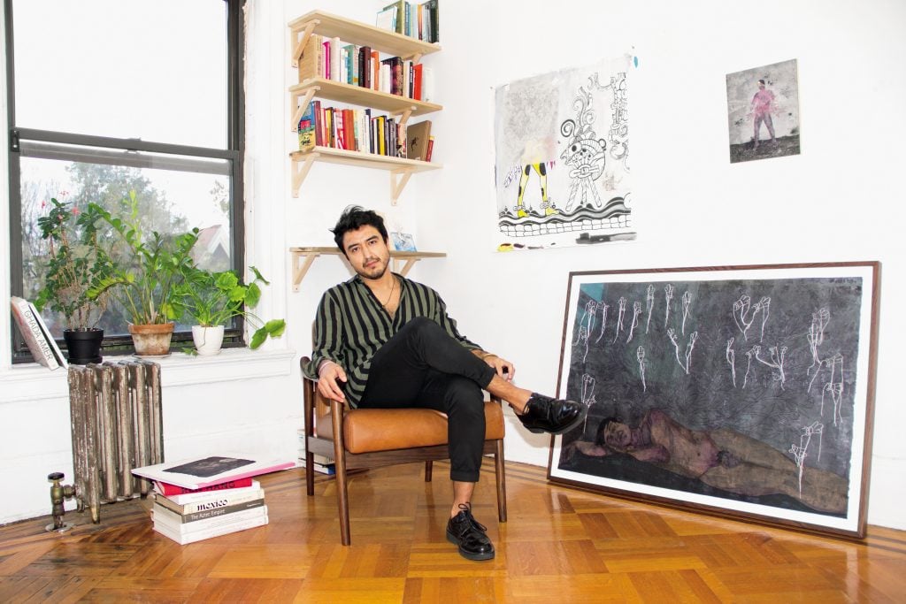 Felipe Baeza in his Brooklyn home surrounded by his art, including a work in progress hanging on the wall. Photo by Sunny Leerasanthanah, ©2021 Jasmin Hernandez.