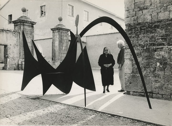 Calder and a nun with <i>Black Widow</i> (1959) outside the Chiesa di San Domenico, Spoleto, 1962. Photograph: Ugo Mulas © Ugo Mulas Heirs. © 2021 Calder Foundation, New York / Artists Rights Society (ARS), New York.
