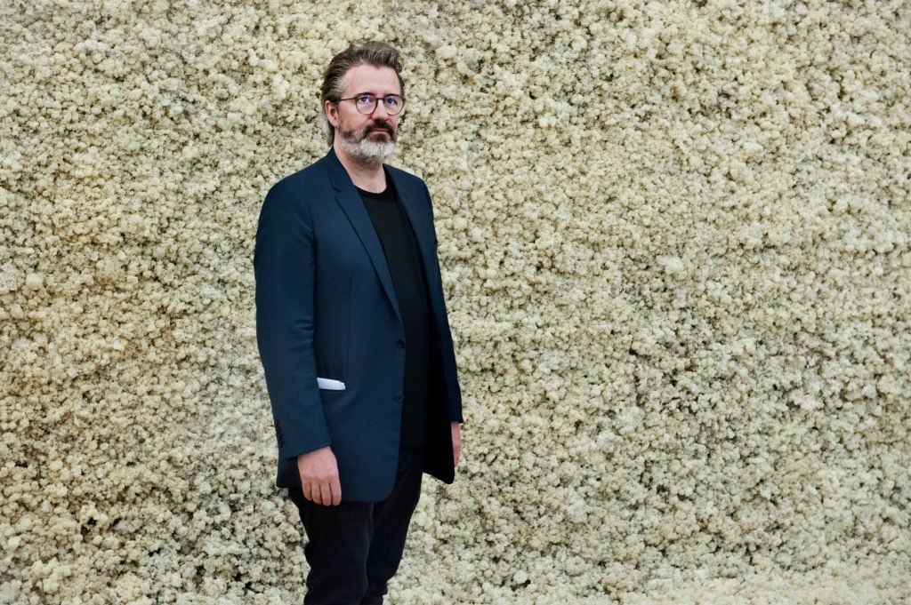 Olafur Eliasson beside his art installation titled Moss Wall at Tate Modern in London on July 9, 2019. Photo Judith Burrows/Hulton Archive/Getty Images.